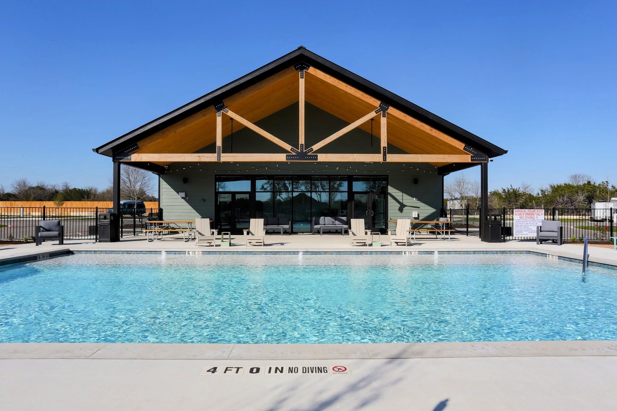 The pool and clubhouse pavilion at a ROAM RV park under a clear Texas sky.